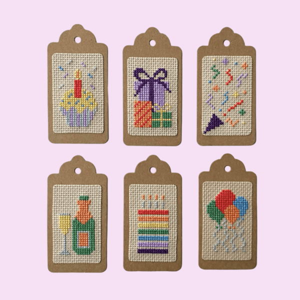 6 birthday cross stitched gift tags in different designs: cupcake, presents, streamer, champagne, cake and balloons